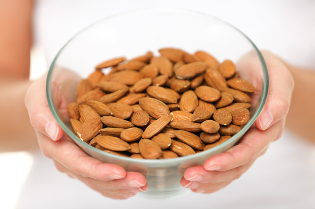 Almonds - woman showing raw almond bowl close up