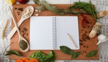 notebook for recipes and spices on wooden board