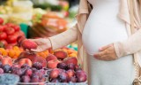 pregnant woman choosing fruits at street market