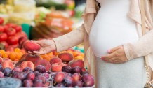 pregnant woman choosing fruits at street market
