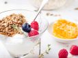 Healthy breakfast. Granola with pumpkin seeds, honey, yogurt and fresh berries in a ceramic bowl on white background.