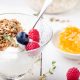 Healthy breakfast. Granola with pumpkin seeds, honey, yogurt and fresh berries in a ceramic bowl on white background.