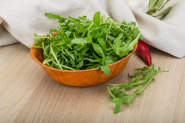 Ruccola leaves mix in the bowl on wooden background
