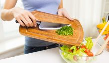 close up of woman with chopped onion cooking salad