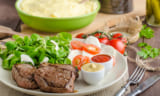 Beef steak with salad, mozzarella and tomatoes, two dip and mashed potato behind
