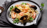 Spaghetti seafood pasta with clams and prawns. White wine glass.