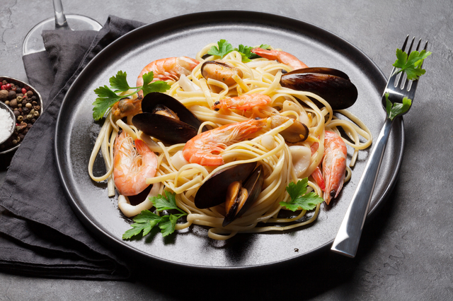 Spaghetti seafood pasta with clams and prawns. White wine glass.