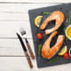 Grilled salmon, salad and condiments on wooden table. Top view with copy space