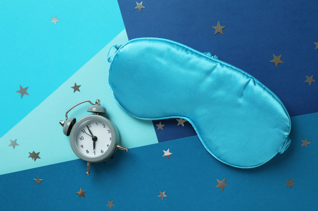 Sleep mask and alarm clock on multicolored background
