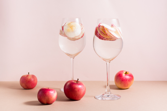 Refreshing cocktail of apple pieces and mineral water in wine gl