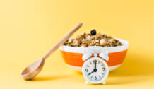 Healthy eating. Alarm clock in front of a baked granola made fro