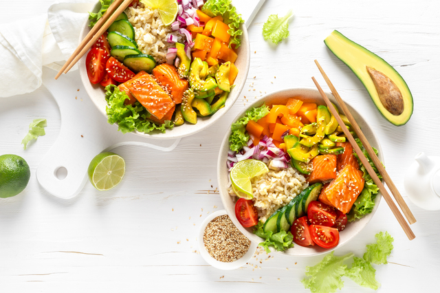 Buddha bowl with grilled salmon fish, fresh cucumber, tomato, onion, sweet pepper, avocado, lettuce salad and rice, healthy balanced eating